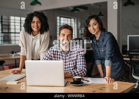 Smiling young designers working together at an office desk Stock Photo