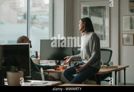 Designer talking with a male coworker during an office break Stock Photo
