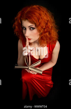 redhead religious lady with finger on lips Stock Photo