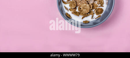Minimalism. Healthy breakfast. cereals with milk in a gray bowl on a pink background. Stock Photo