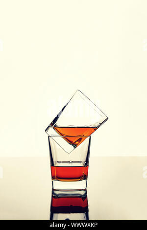 Whiskey, rum or cognac in two glasses on the table with reflection. Concept: luxury alcohol. Stock Photo
