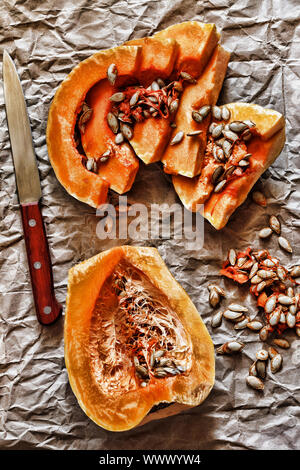 Pieces of ripe pumpkin and seeds on a background of crumpled packing paper. Stock Photo