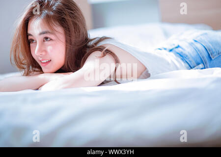 Beautiful girl taking pictures in her room lying on the bed and sitting and reading is very interesting, ahihi Stock Photo
