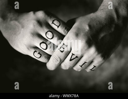 Man with 'Good' and 'Evil' (fake) tattoos on his fingers. Stock Photo