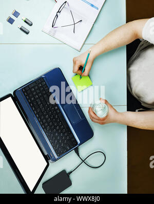 Young freelancer working at home at a table using a laptop Stock Photo