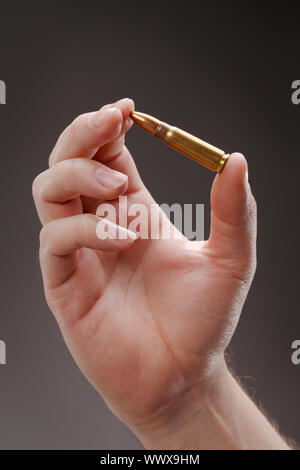 Hand holding an assault rifle cartridge Stock Photo - Alamy