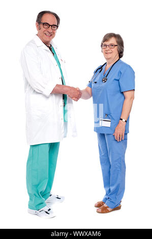 Full body portrait of two senior medical persons shaking hands isolated on white background Stock Photo