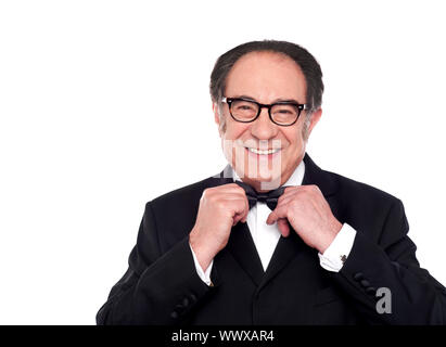 Cheerful old man in classical tuxedo adjusting his bow Stock Photo