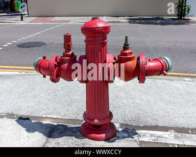 Two sided red roadside fire hydrant on a pavement in Hamilton Bermuda Stock Photo