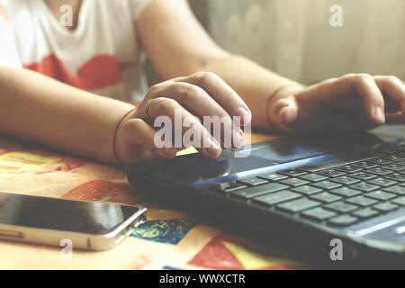 A woman freelancer works at her computer at home. The hands and keyboard of a laptop closeup.Concept Stock Photo