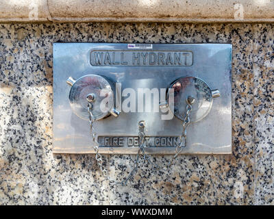 A double wall mounted fire hydrant on a polished granite wall in Hamilton Bermuda Stock Photo