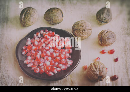 Pomegranate fruits on the plate and walnuts. Stock Photo