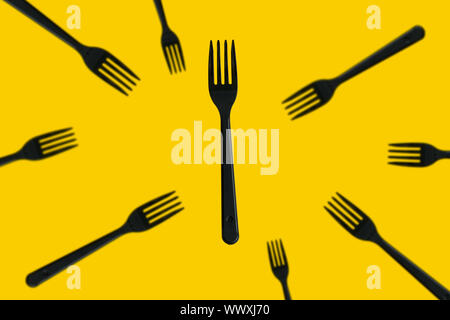 creative still life with black plastic forks flying on a yellow background Stock Photo