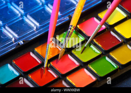 Closeup of a palette of watercolor paints with three brushes Stock Photo
