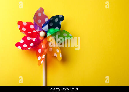 Childrens colorful windmill toy isolated on yellow background Stock Photo