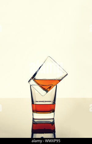 Whiskey, rum or cognac in two glasses on the table with reflection. Concept: luxury alcohol. Stock Photo