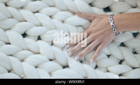 The girl is stroking the merino white plaid. Hand close-up. Stock Photo