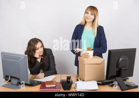 New employee in the office happily keeps things close sad colleague Stock Photo