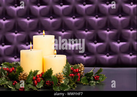 Advent flower arrangement with burning candles in front of a button tufted purple silk background Stock Photo