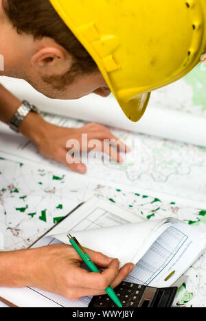 construction worker calculating and checking documents, maps and charts Stock Photo