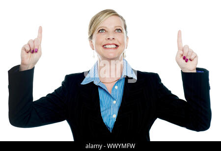 Corporate lady pointing upwards with both hands and looking up as well Stock Photo