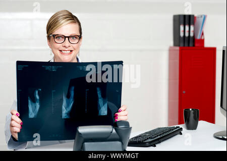 Female surgeon showing x-ray reports to camera. Siting in her chamber Stock Photo