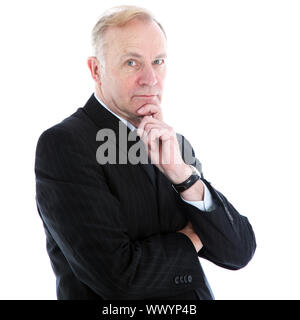 Pensive thoughtful middle-aged businessman with a serious expression standing looking at the camera with his chin resting on his hand Stock Photo