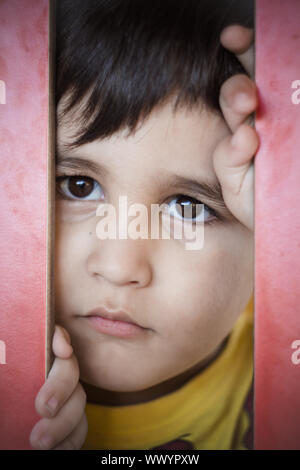 Sad, Brunette boy putting funny faces in an outdoor park Stock Photo