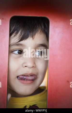 Brunette boy putting funny faces in an outdoor park Stock Photo