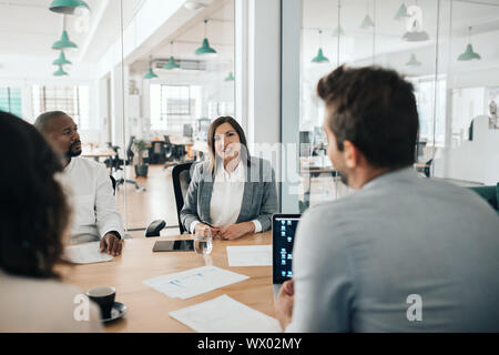 Smiling businesswoman talking with colleagues during an office meeting Stock Photo