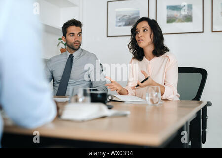 Young businesswoman explaining ideas to coworkers during an office meeting Stock Photo
