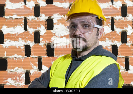 Engineer Do it yourself, man dressed in yellow builder helmet with protective glasses ready to start the construction work Stock Photo