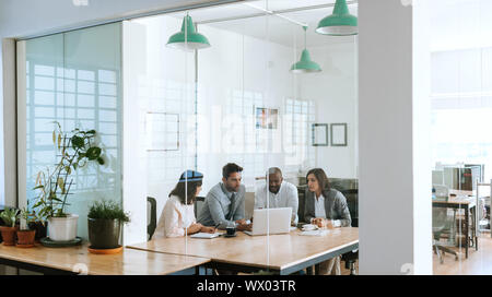 Diverse businesspeople using a laptop together in an office boardroom Stock Photo