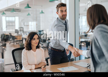 Smiling young businessman shaking hands with an office colleague Stock Photo