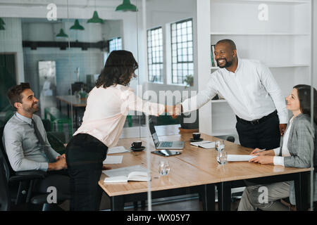 Smiling businessspeople standing in a boardroom shaking hands together Stock Photo