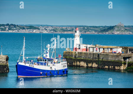 Fishing boat coming into the harbour at the village of Newlyn with St. Michael's Mount at Marazion in the distance, Cornwall, England, United Kingdom Stock Photo