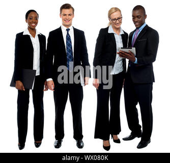 Corporate team of four posing with tablet pc. One team using tablet and other members facing camera Stock Photo