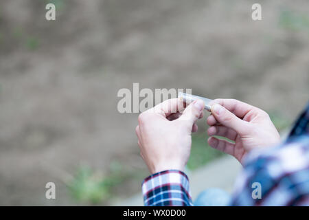 Two hands rolling a cigarette with a selective focus. Stock Photo