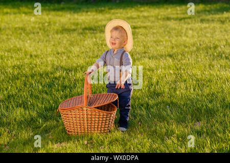 Toddler child outdoors. One year old baby boy wearing straw hat with picnic basket Stock Photo