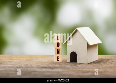 Home loan, mortgage, a property investment for future concept. A small residence house model and wooden block on wood table with nature background. A Stock Photo