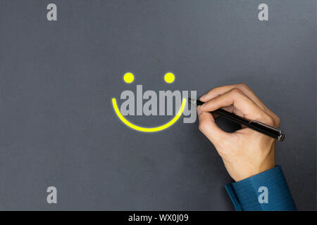 Conceptual the customer responded to the survey. The client using pen write happy face smile icon on blackboard. Depicts that customer is very satisfi Stock Photo