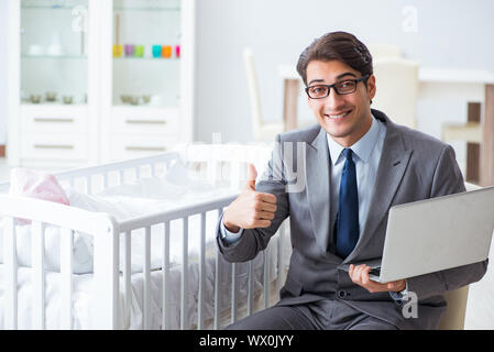 Young businessman trying to work from home caring after newborn baby Stock Photo