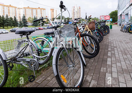 Minsk, Belarus - July 17, 2019: Bike-stand with many bicycles standing on wet pavement tiles Stock Photo