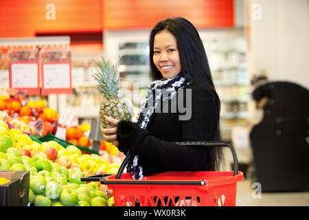 Portrait of a cheerful young woman buying fruits in the supermarket Stock Photo
