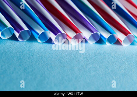 Blue, purple and red plastic straws on a blue paper background. Copy space for text Stock Photo