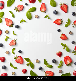 Frame of fruit pattern with strawberries, blueberries and mint leaves on a white background, flat lay Stock Photo