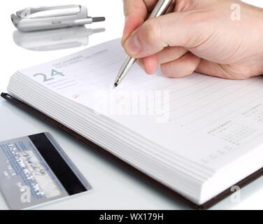 A notebook open on december twenty fourth, a credit card and a cellphone. Stock Photo