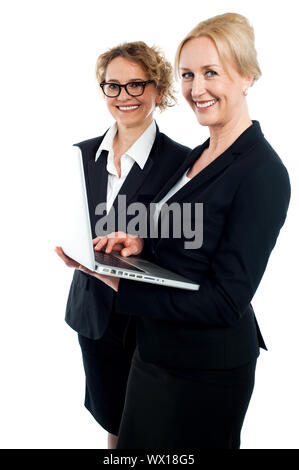 Side view portrait of two corporate women working on laptop isolated against white background Stock Photo