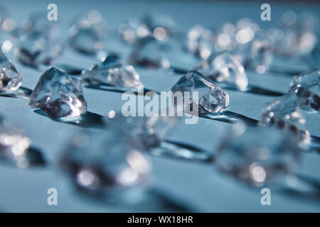 Sparkling ice cubes on a blue paper background. Blurred Background Stock Photo