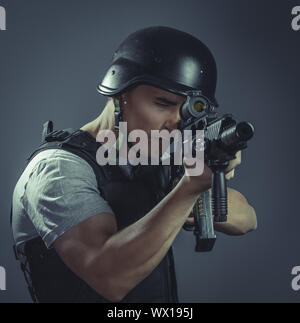 Security, paintball sport player wearing protective helmet aiming pistol ,black armor and machine gun over blue chroma backgroun Stock Photo